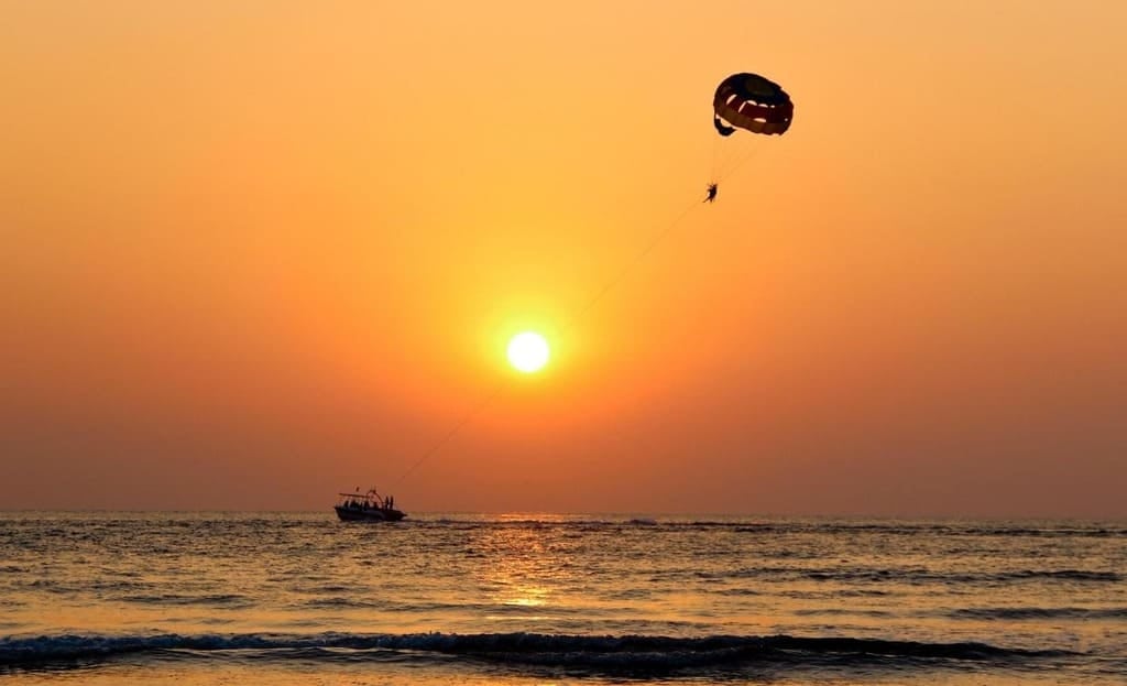 Parasailing above the Montenegro coast at sunset with a boat on the sea below