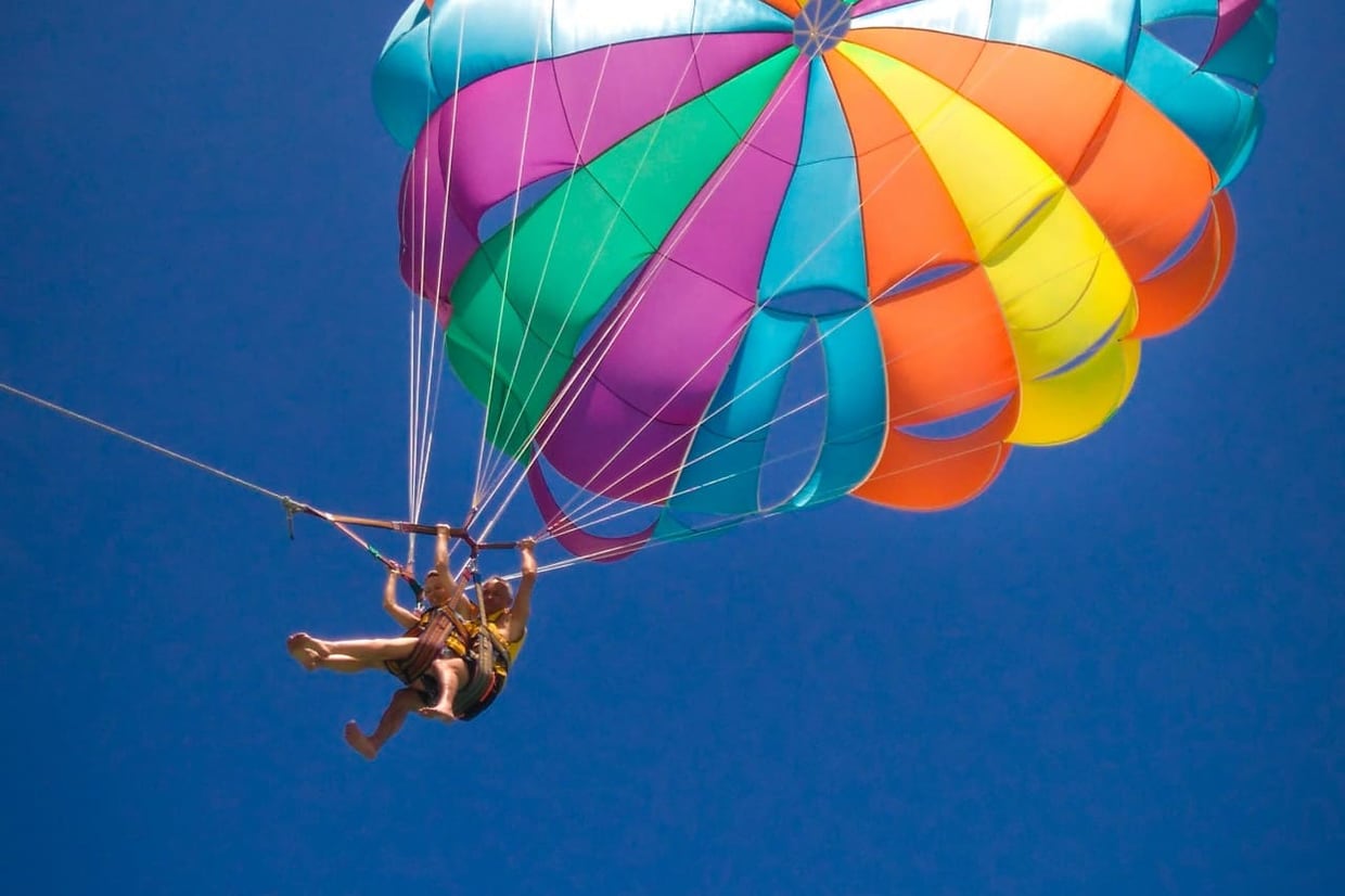 Tandem parasailing above the Montenegro coast with a colorful canopy against blue sky